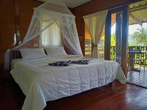 a bedroom with a large white bed with a canopy at Three Monkeys Bungalows Koh Yao Noi in Ko Yao Noi