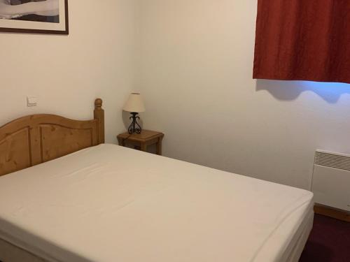 - un lit blanc dans une chambre avec une lampe sur une table dans l'établissement Appartement cosy à Orcières avec parking et WIFI gratuit, 4 personnes - FR-1-636-218, à Orcières