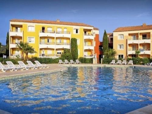 une piscine en face de deux bâtiments dans l'établissement Studio cabine 4 pers. avec piscine commune et parking - FR-1-226-510, à Roquebrune-sur Argens