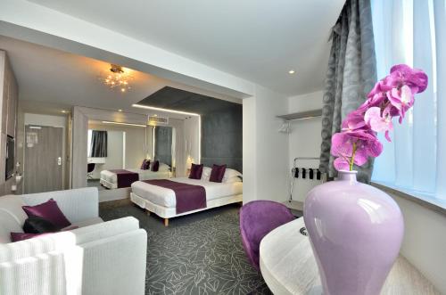 una sala de estar con un jarrón púrpura con flores. en Cézanne Hôtel Spa en Cannes