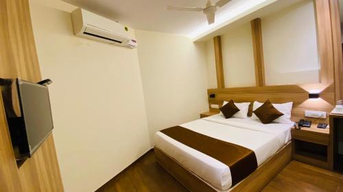 a hotel room with a bed and a television at Hotel Plaza Heights by RAK Rooms, Mangaluru in Mangalore
