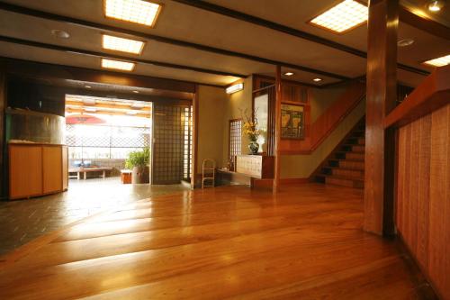a large room with a wooden floor and a staircase at Sennennoyu Koman in Toyooka