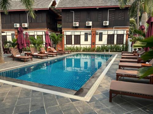 einen Pool mit Liegestühlen neben einem Gebäude in der Unterkunft Mahasok hotel in Luang Prabang