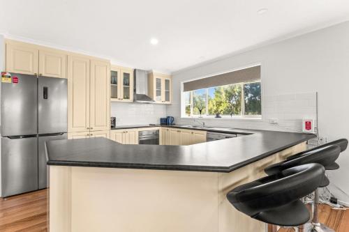 a kitchen with a black counter top and a refrigerator at Seas the day in Kilcunda