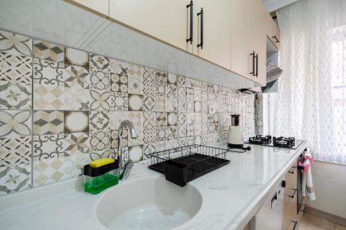 a white kitchen with a sink and a tile wall at Steps away from historical Bursa in Bursa