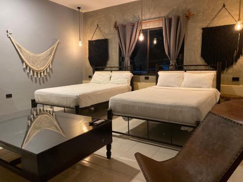 a room with two beds and a coffee table at Ariché Valladolid Hotel & Hostal in Valladolid