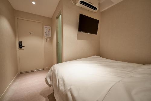 a bedroom with a white bed and a flat screen tv at Life in Euljiro in Seoul