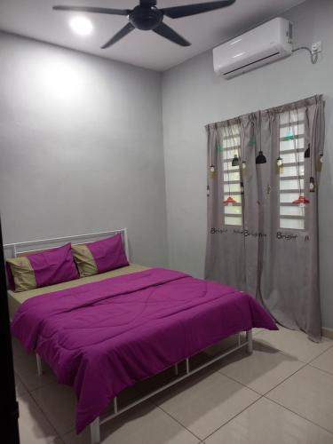 a bedroom with a purple bed with a ceiling fan at Yaths homestay in Butterworth