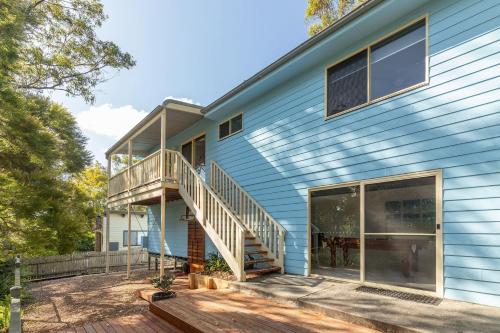 a blue house with a porch and a deck at Montes Lake House in Smiths Lake