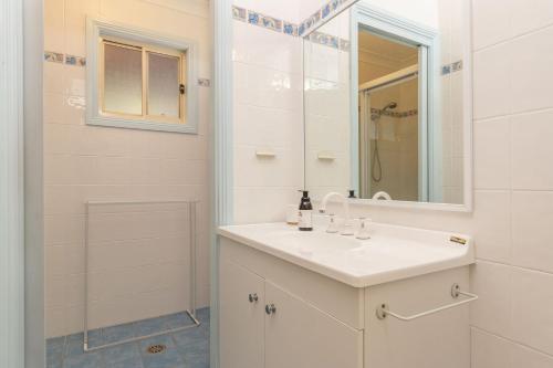 a white bathroom with a sink and a mirror at Montes Lake House in Smiths Lake