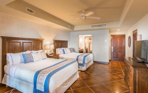 a hotel room with two beds and a flat screen tv at The Club at Hacienda del Mar in Cabo San Lucas