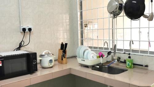 a kitchen counter with a sink and a microwave at Sandakan Homestay in Sandakan