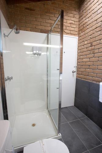 a bathroom with a glass shower with a toilet at Goldfields Motel in Stawell