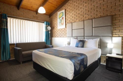 a hotel room with a bed and a couch and a chair at Goldfields Motel in Stawell