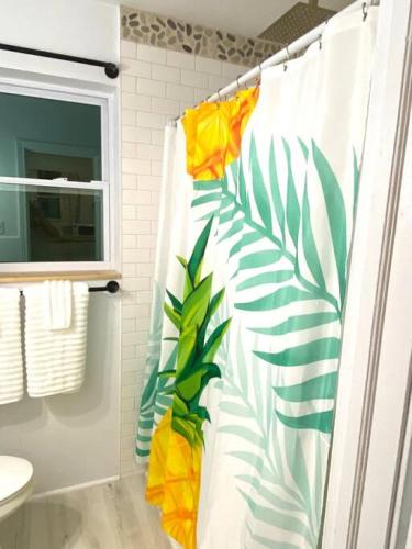 a bathroom with a shower curtain with a tropical print at Pineapple Shores Retro Inn 3 in Daytona Beach