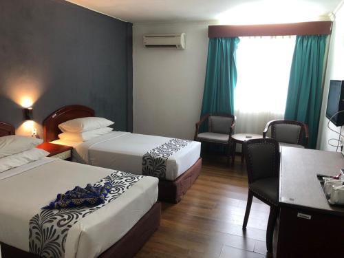 a hotel room with two beds and a desk at Hotel Seri Malaysia Taiping in Taiping