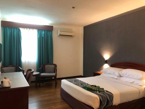 Hotel Seri Malaysia Taiping في تايبينغ: غرفة فندقية بسرير وطاولة وكراسي