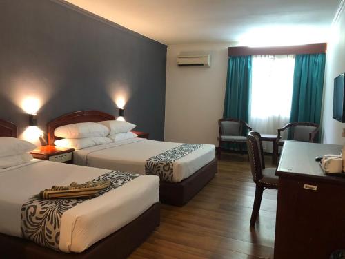 a hotel room with two beds and a desk at Hotel Seri Malaysia Taiping in Taiping