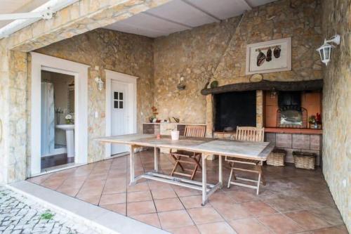 a kitchen with a table and a stone wall at Quinta do Alto dos Pinheiros in São João da Ribeira