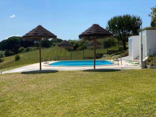 a swimming pool with umbrellas on top of a yard at Quinta do Alto dos Pinheiros in São João da Ribeira