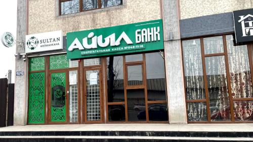 una tienda con una señal verde en la parte delantera de un edificio en Sultan Jalal-Abad en Jalal-Abad
