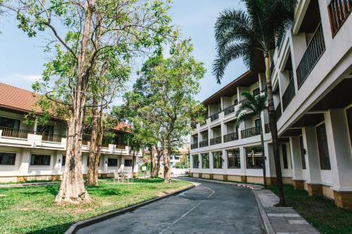 an empty street in front of a building with trees at President Hotel Udonthani in Udon Thani