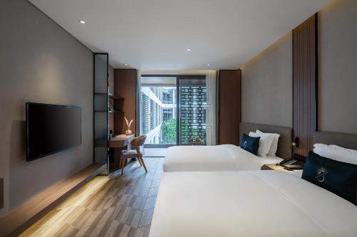 een hotelkamer met 2 bedden en een flatscreen-tv bij Percent Hotel Yangshuo in Yangshuo