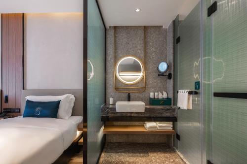 a bathroom with a bed and a sink and a mirror at Percent Hotel Yangshuo in Yangshuo
