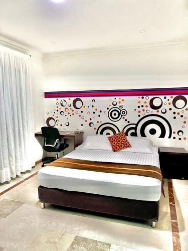 a bedroom with a large bed with a colorful headboard at Hotel Ingenio Reina Isabel in Cali