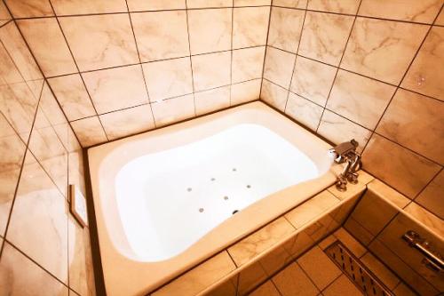 a bath tub in a bathroom with a tiled wall at Hotel Pasion Resort (Adult Only) in Fukushima