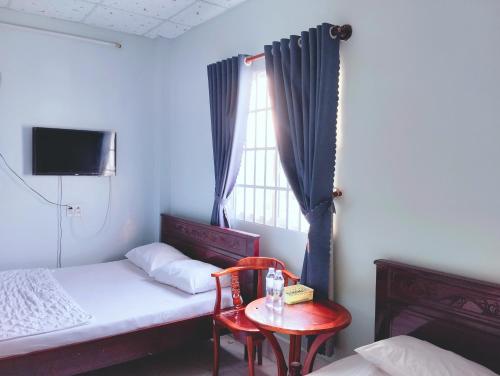sypialnia z łóżkiem, stołem i oknem w obiekcie Nhà nghỉ Thành Lợi w mieście Ấp Rạch Mẹo