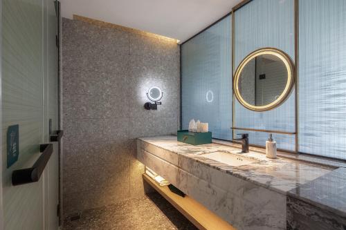 La salle de bains est pourvue d'un lavabo et d'un miroir. dans l'établissement Percent Hotel Yangshuo, à Yangshuo
