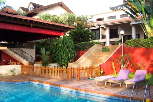 a swimming pool with two chairs next to a house at Villa Anakao Abidjan in Abidjan