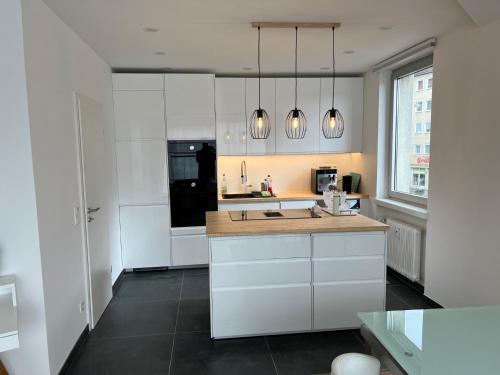 cocina con armarios blancos y nevera negra en Lovely HOME Suite in Nuremberg, en Núremberg