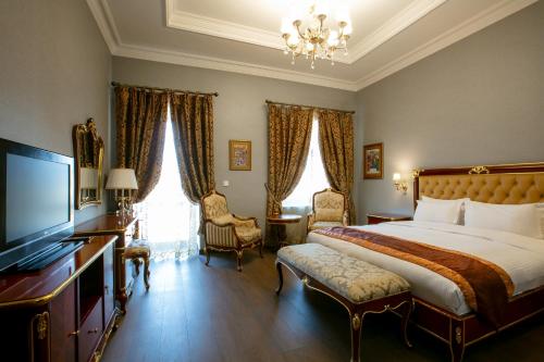 a bedroom with a large bed and a television at Shah Palace Luxury Museum Hotel in Baku