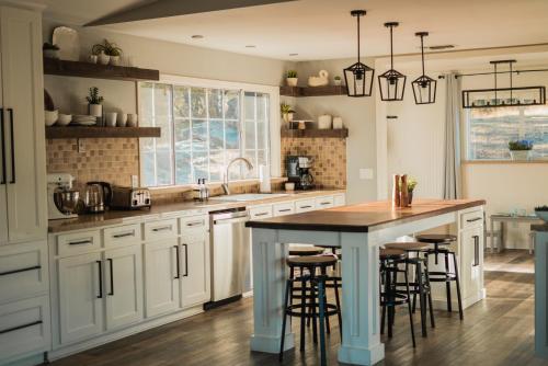 a kitchen with white cabinets and a island with bar stools at Family Farmhouse by Casa Oso with views and spa in Ahwahnee