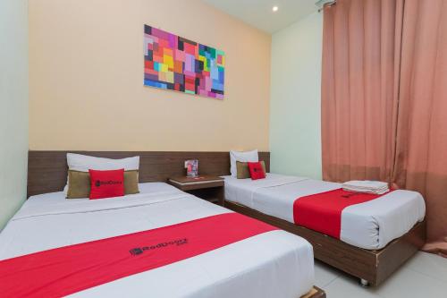 two beds sitting next to each other in a room at RedDoorz near Alun Alun Madiun in Madiun