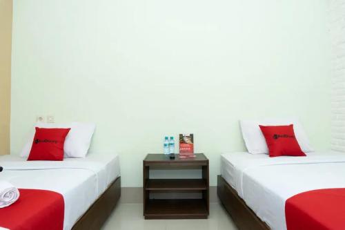 two beds with red and white pillows in a room at RedDoorz near Alun Alun Madiun in Madiun
