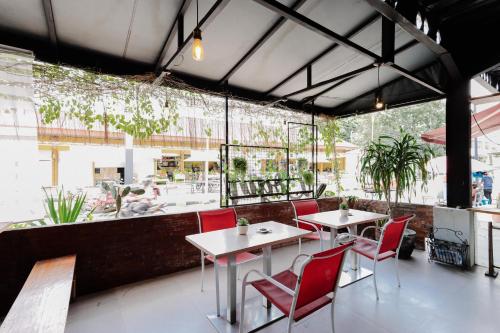 a restaurant with red chairs and tables and a large window at RedDoorz near Alun Alun Madiun in Madiun