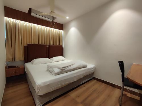 um quarto com uma cama com lençóis brancos e uma secretária em STAYMAKER Hotel Mohan Palace em Baharampur