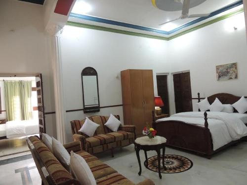 a bedroom with a bed and a couch and chairs at Kunjpur Guest House in Allahābād