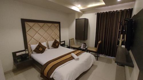 um quarto com uma cama grande e uma televisão em Hotel Flair Inn em Ahmedabad