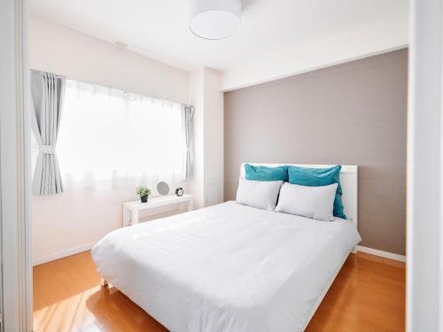 a white bedroom with a large white bed and a window at Nakano Apartment hotel in Tokyo