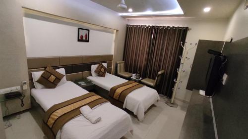 a hotel room with two beds and a television at Hotel Flair Inn in Ahmedabad