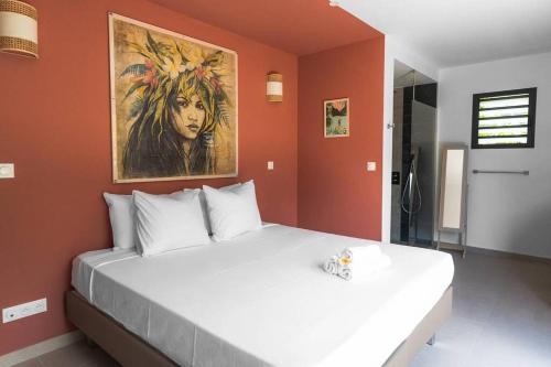ein Schlafzimmer mit einem großen Bett und einem Gemälde an der Wand in der Unterkunft Ô 3 CAP - Magnifique Villa 8 personnes avec piscine, face à la plage de Boucan-Canot in Saint-Gilles-les-Bains