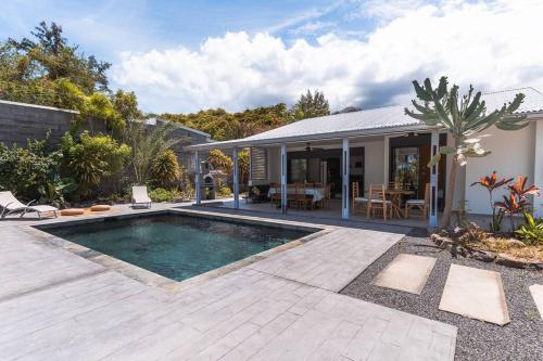 a backyard with a swimming pool and a house at VILLA Ô 3 CAP - Magnifique Villa - classée 4 étoiles - Piscine CHAUFFEE - 4 ch - 8 personnes - accès direct à la plage et à l'esplanade de BOUCAN CANOT in Saint-Gilles les Bains