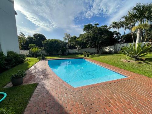 a swimming pool in a yard with a brick driveway at Shore Break, 1 bedroom apartment in Umdloti