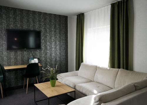 sala de estar con sofá y TV en Hotel George, en Nadarzyn