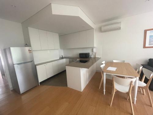 a kitchen and dining room with a table and a refrigerator at Snowhaven in Jindabyne