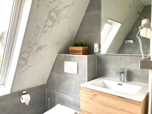 ein Bad mit einem Waschbecken und einem Spiegel in der Unterkunft Maralong Noordwijk in Noordwijk